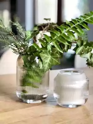 Wazon z grubego transparentnego szkła. Wazon posiada strukturę karbowanego szkła.  Pięknie wyeksponujesz w nim rośliny,  a światło przenikając przez szkło da niezwykły efekt. Do wazonu polecamy świecę sojową,  zapachową w pojemniku z tego samego szkła. Wysokość wazonu: 13cm Średnica wazonu