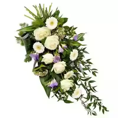 Bukiet Kondolencyjny II Wyraź swój smutek tym niezwykłym bukietem kwiatów w biało-fioletowej tonacji. W skład kompozycji wchodzą róże,  gerbery oraz frezje. Całość jest udekorowana zielonymi dodatkami. Do bukietu wykonanego przez lokalną kwiaciarnię Euroflorist istnieje możliwość dołączeni